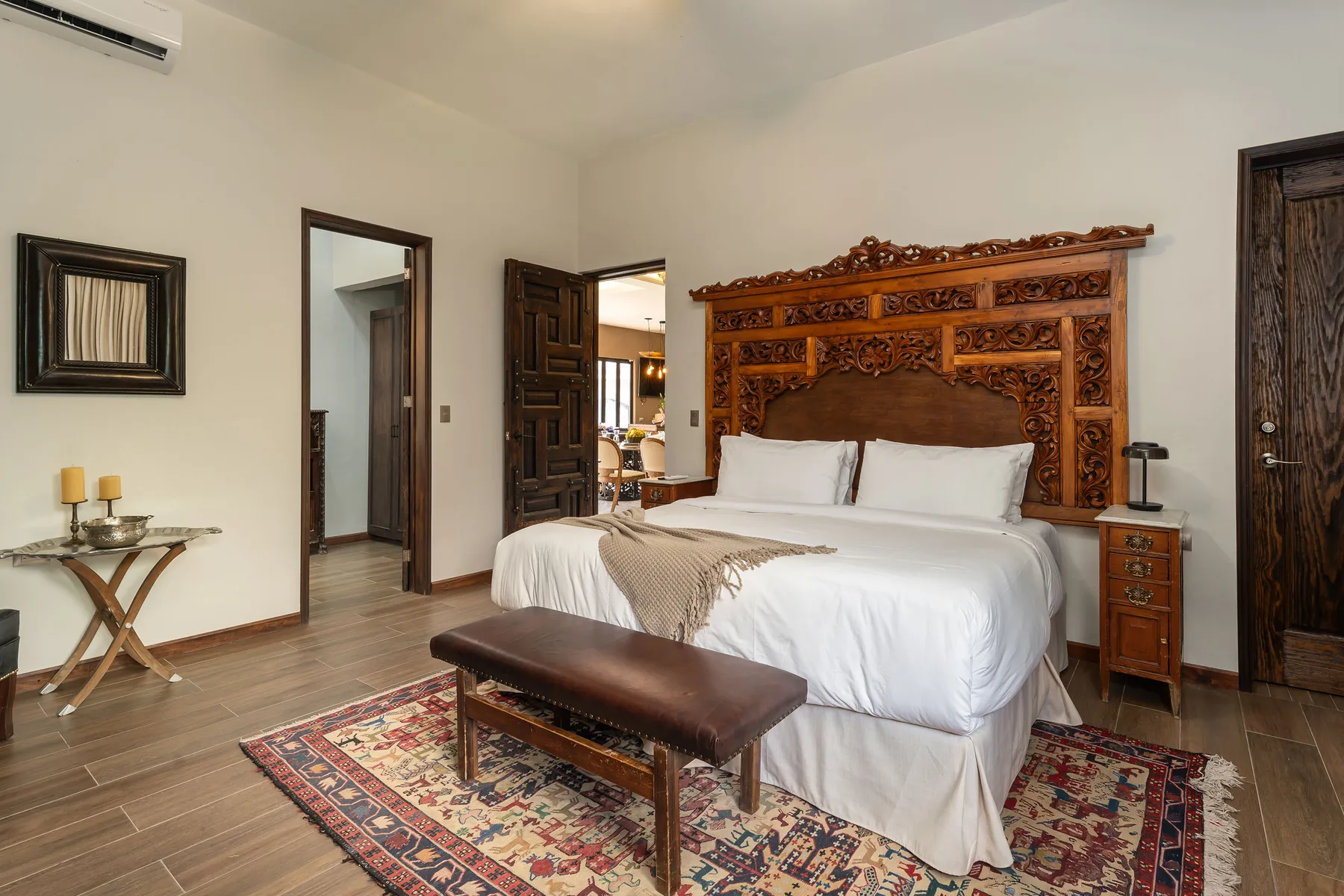 A bedroom with a large bed, carved wooden headboard, and patterned rug.
