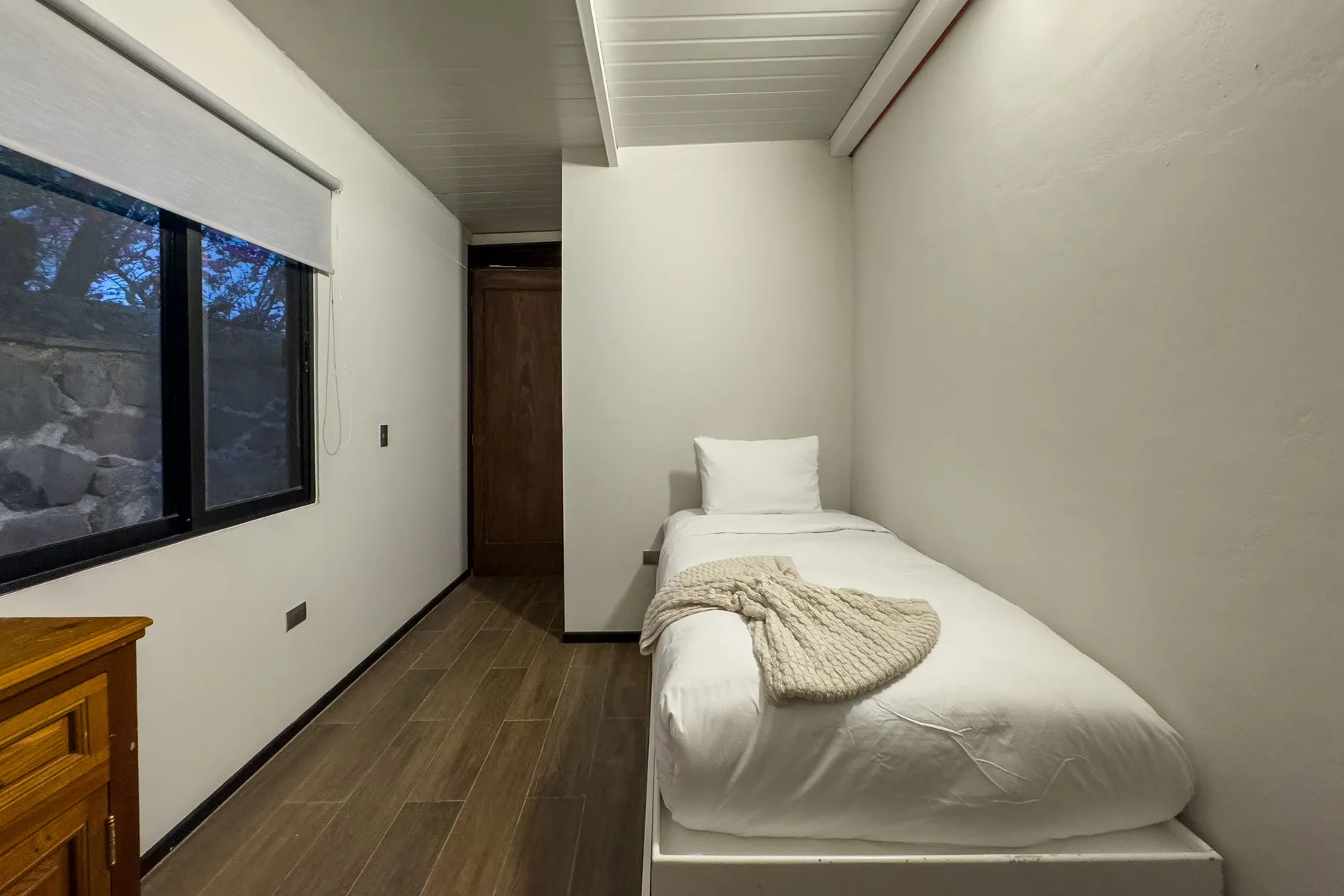 A compact bedroom with a single bed and a large window.