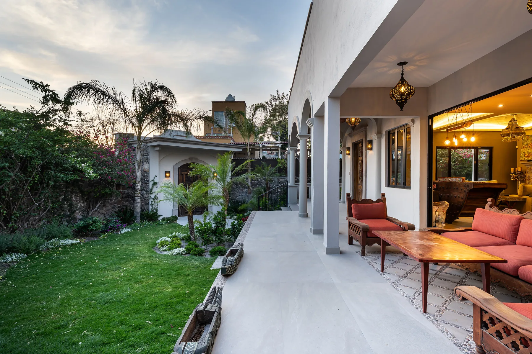 A covered patio with seating overlooks a landscaped garden.