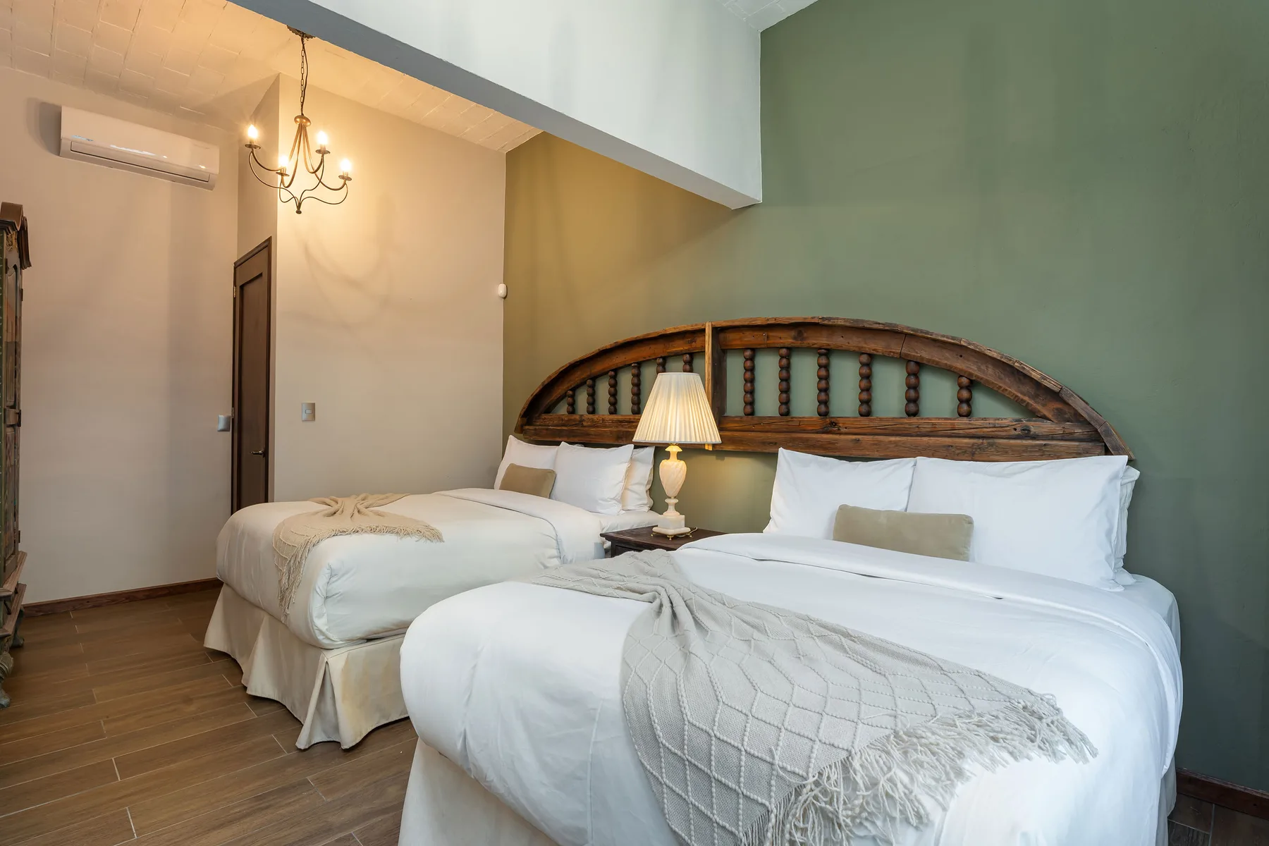 A bedroom with two beds, white bedding, and a curved wooden headboard.