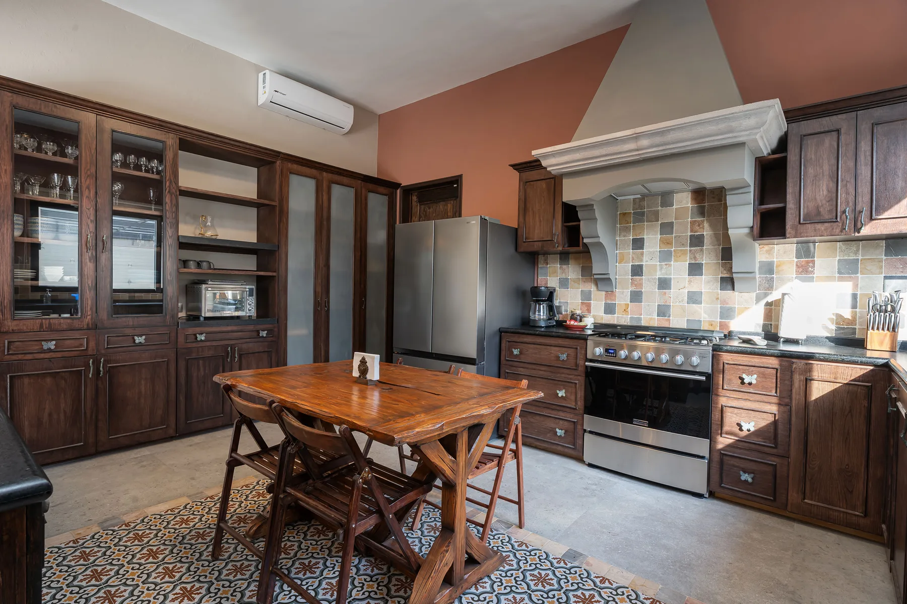 A spacious kitchen with dark wood cabinets, a tiled backsplash, and a central dining table.