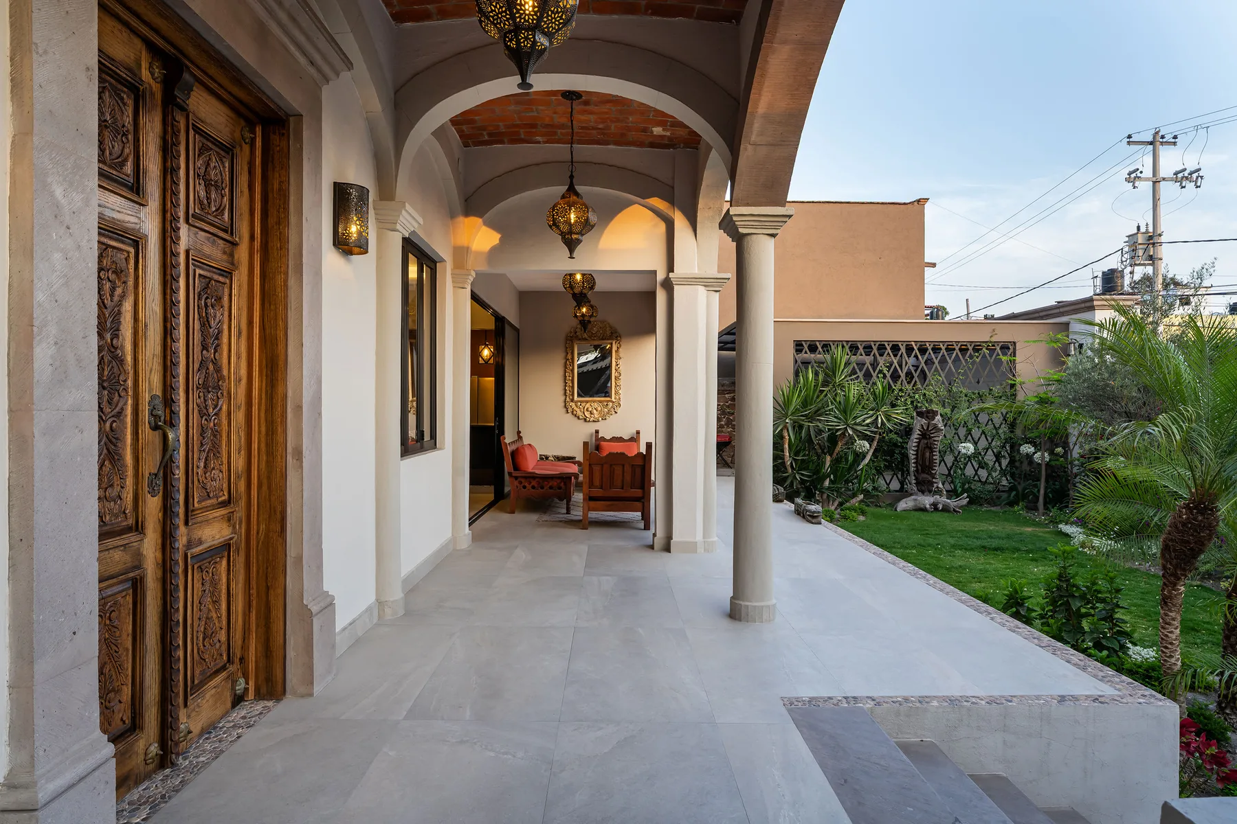 A covered outdoor passage with arches opens onto a garden.