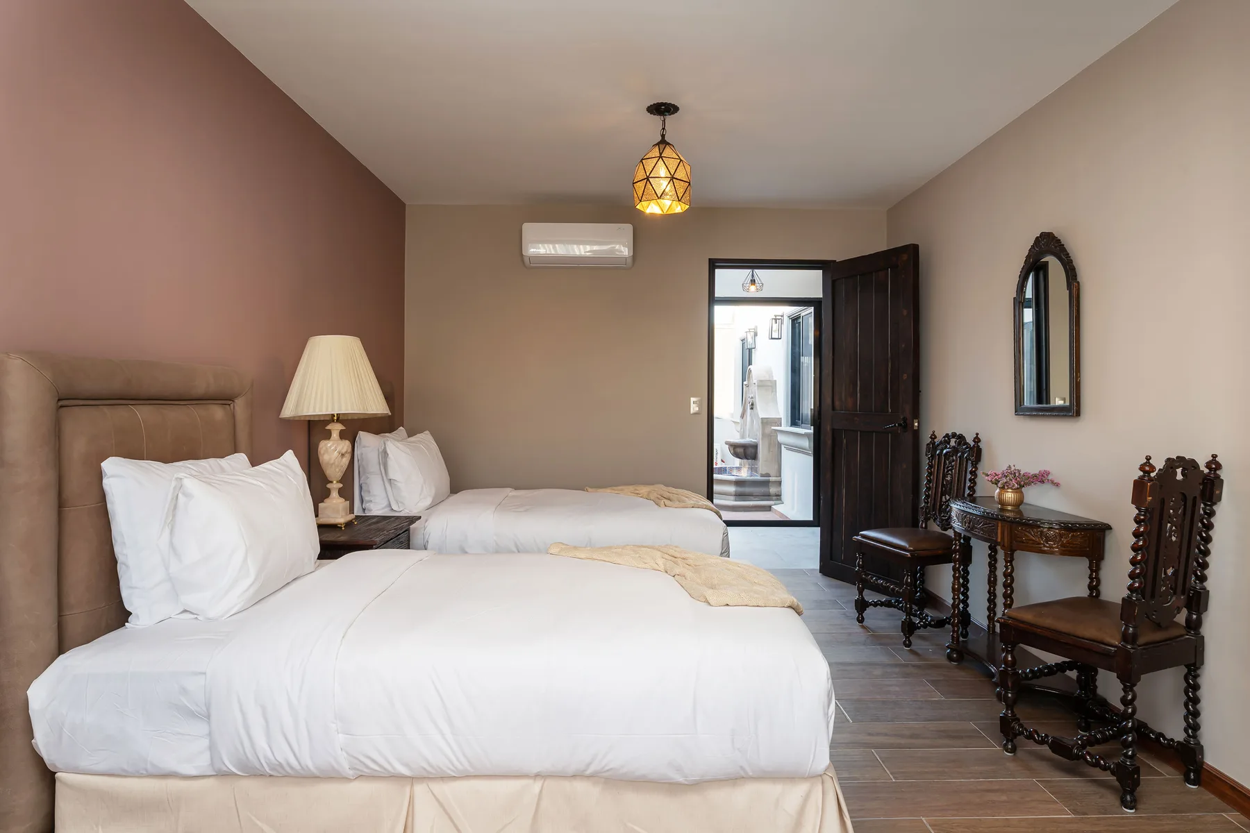 A bedroom with two beds, bedside tables, and an open door.