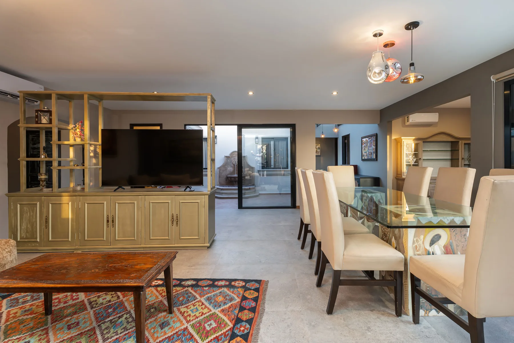A modern living and dining area with a glass dining table and television.