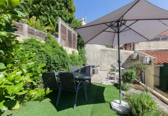 An outdoor patio with a table and seating beneath a large umbrella.