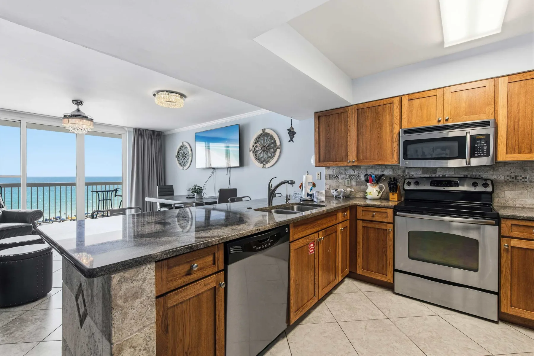 Una cocina luminosa con gabinetes de madera, una isla grande y ventanas con vista al agua.