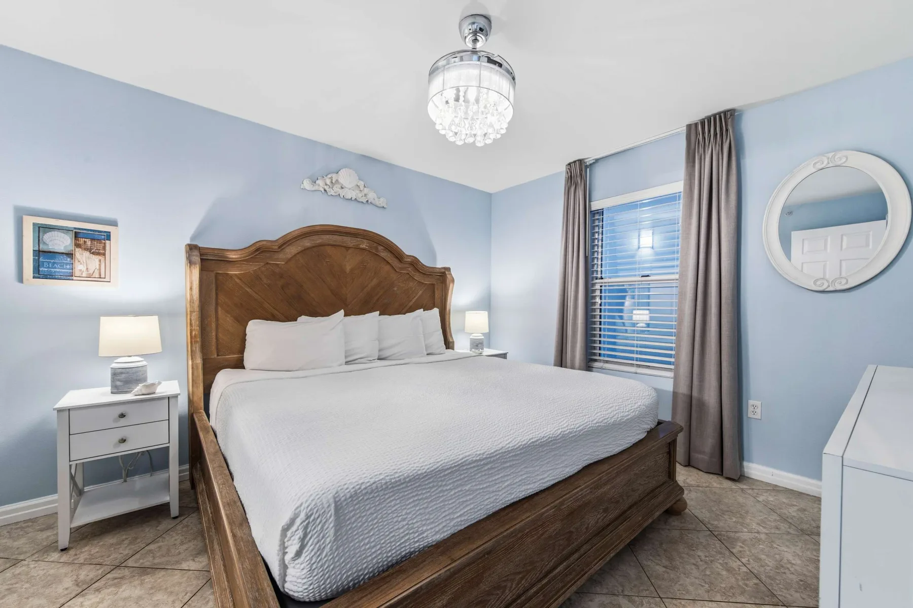 Un dormitorio con una cama de madera, ropa de cama blanca y paredes azules.