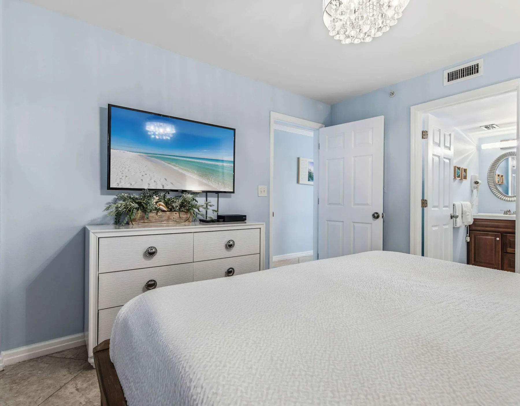 Un dormitorio con cama, cómoda y televisor montado en la pared.