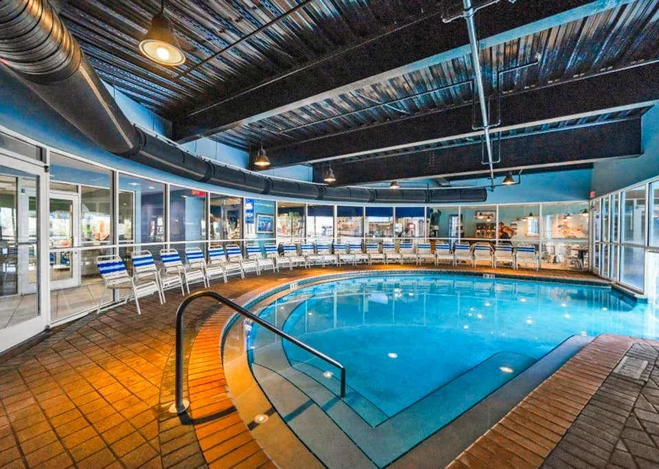 Zona común: Piscina cubierta rodeada de asientos y grandes ventanas.