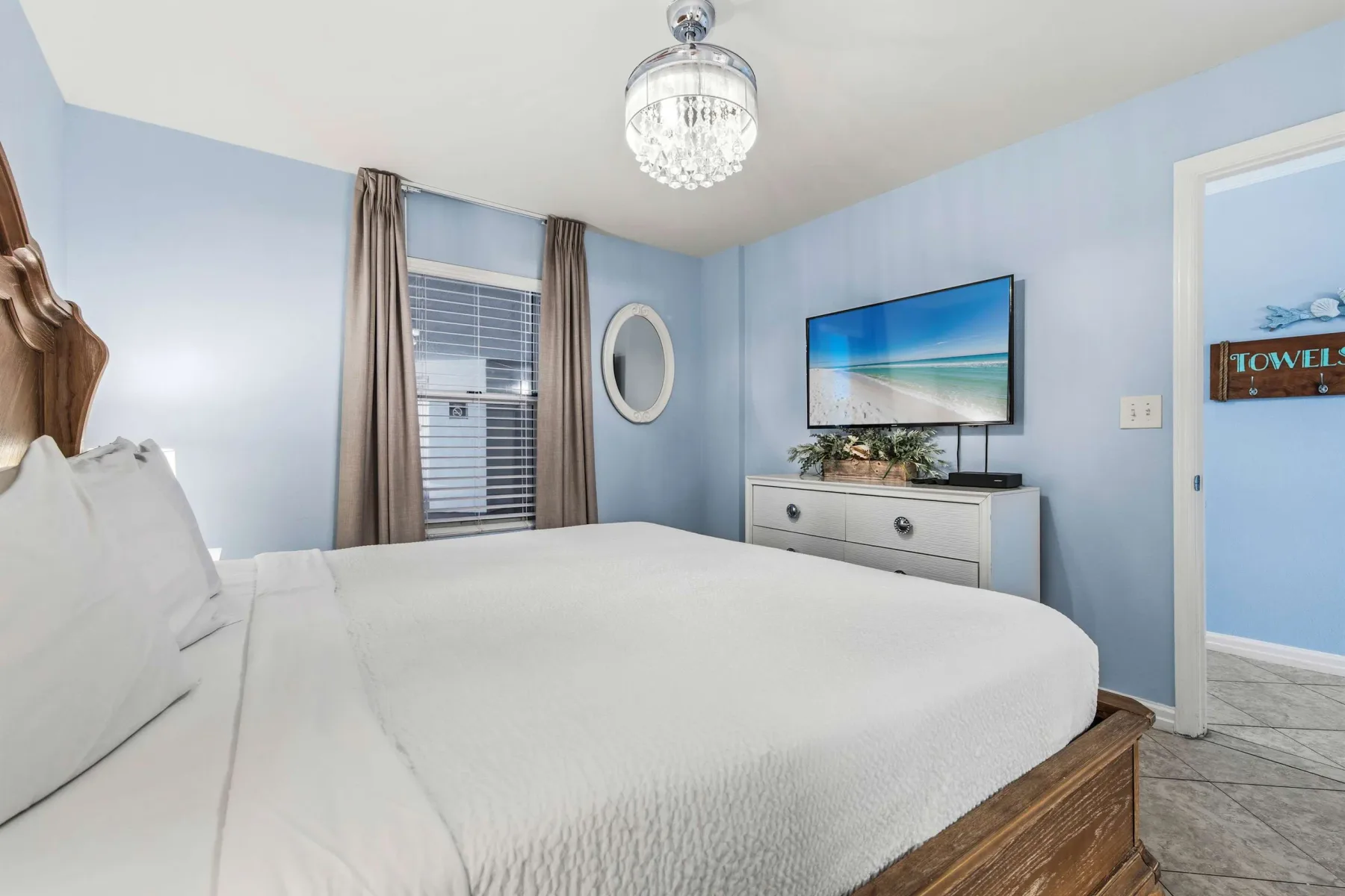 Un dormitorio luminoso con una cama grande, paredes azules y una ventana con cortinas.