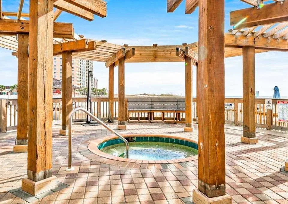 Zona común: Una piscina al aire libre está bajo una pérgola de madera, sobre una terraza de baldosas.
