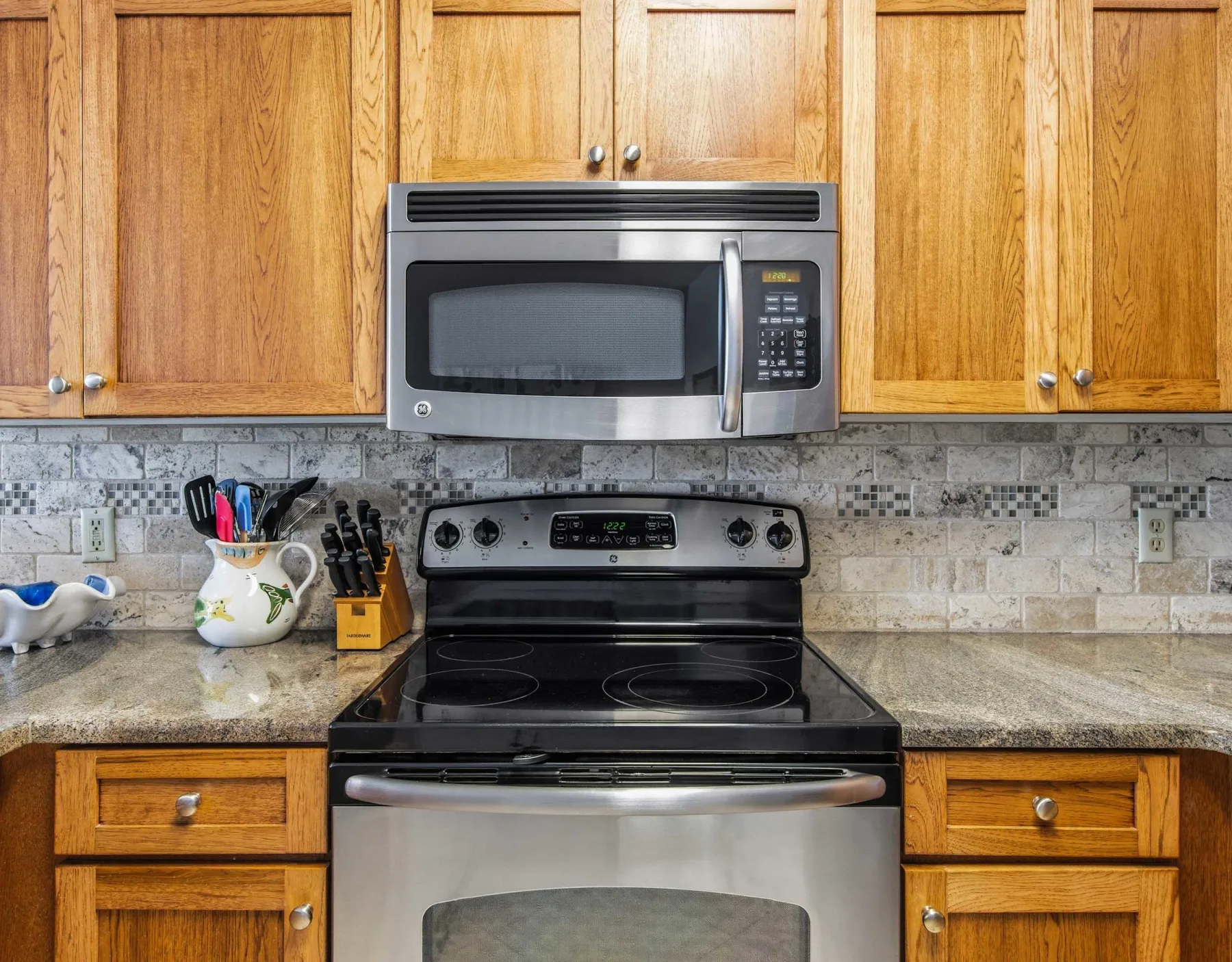 Una cocina con una estufa de acero inoxidable bajo un microondas y gabinetes de madera.