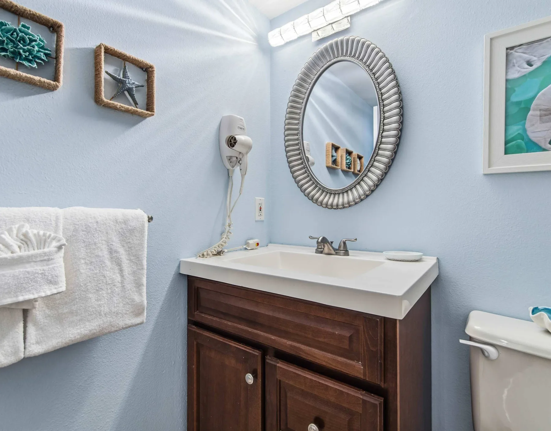 Un baño azul claro con lavabo, espejo de pared y toallero.