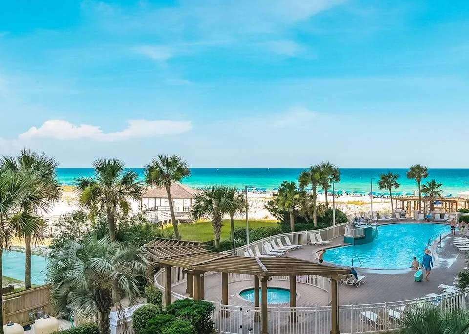 Zona común: Una piscina junto a una playa de arena, con palmeras a lo largo de la costa.
