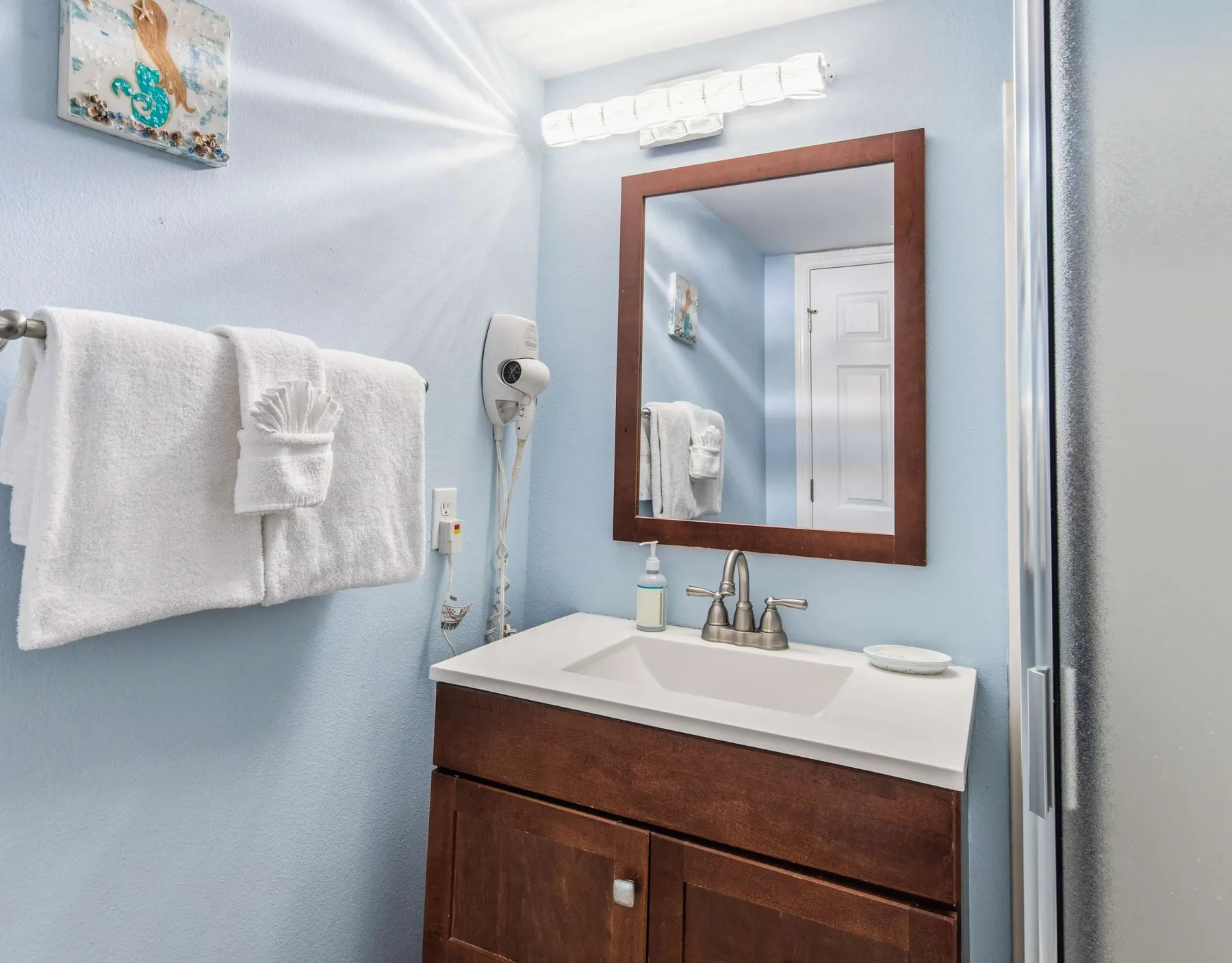 Un lavabo de baño con espejo y toallas en una pared azul claro.