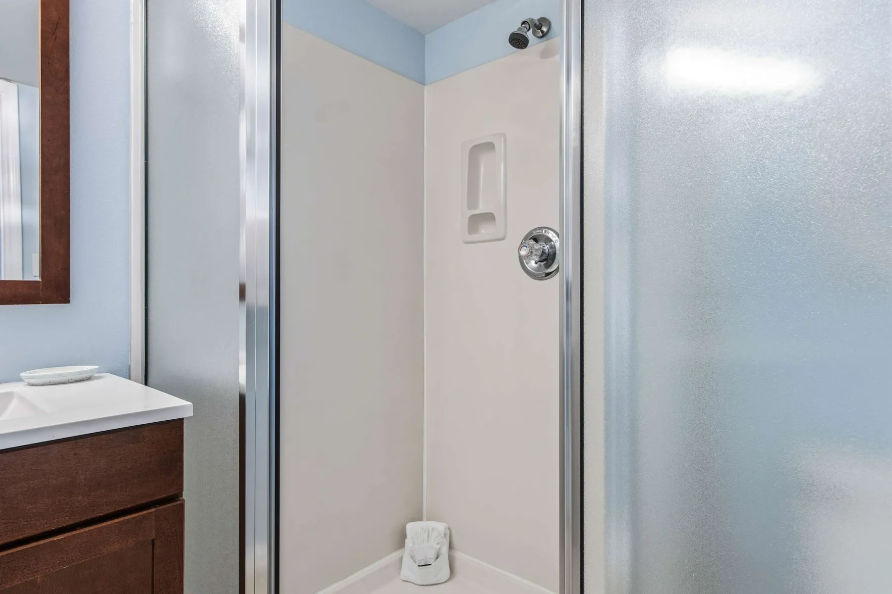 Zona de ducha del baño con un nicho en la pared y accesorios cromados.