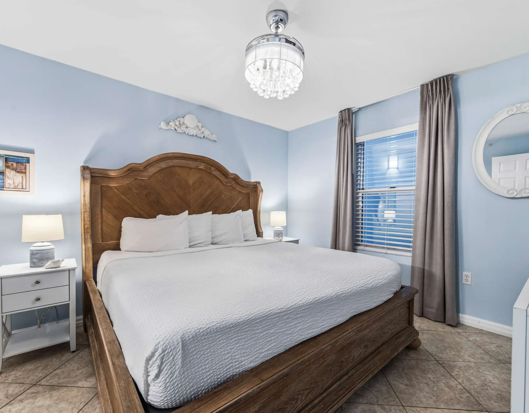 Un dormitorio con una cama grande de madera, ropa de cama blanca y una ventana con cortinas.