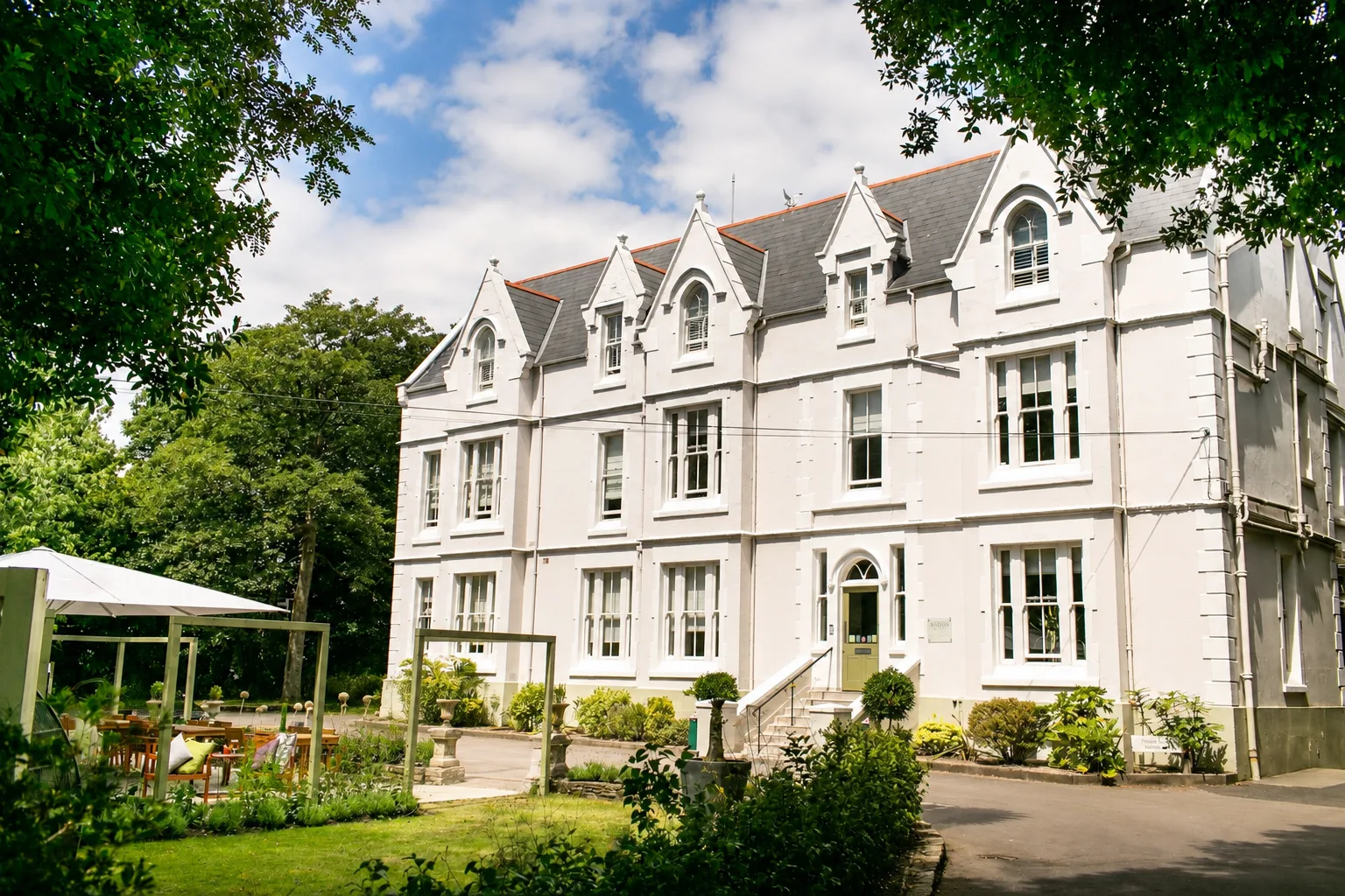 Representative hotel space: A large white building with steep gables stands beside a landscaped garden.