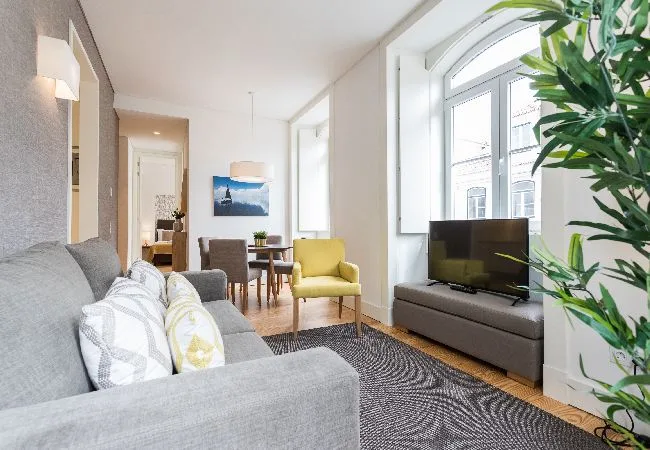 A bright living room with seating, a television, and large windows.