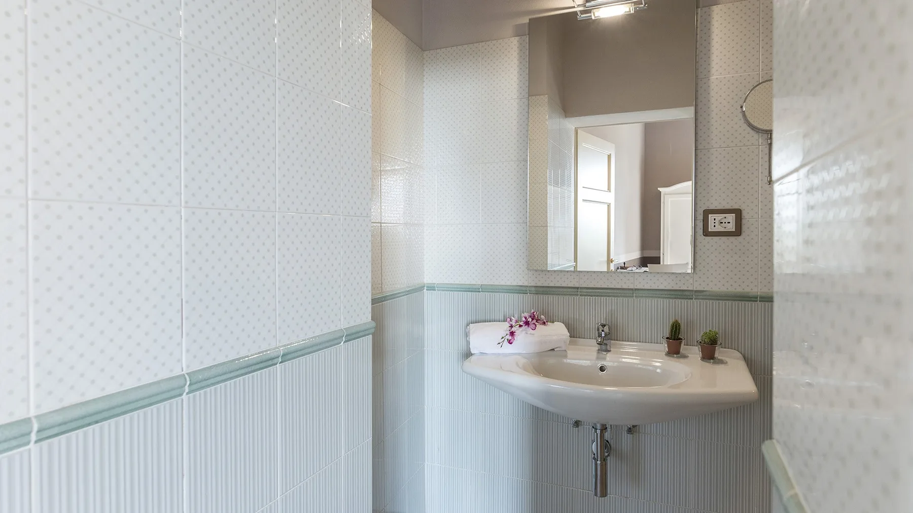 Un baño con azulejos, lavabo y espejo.