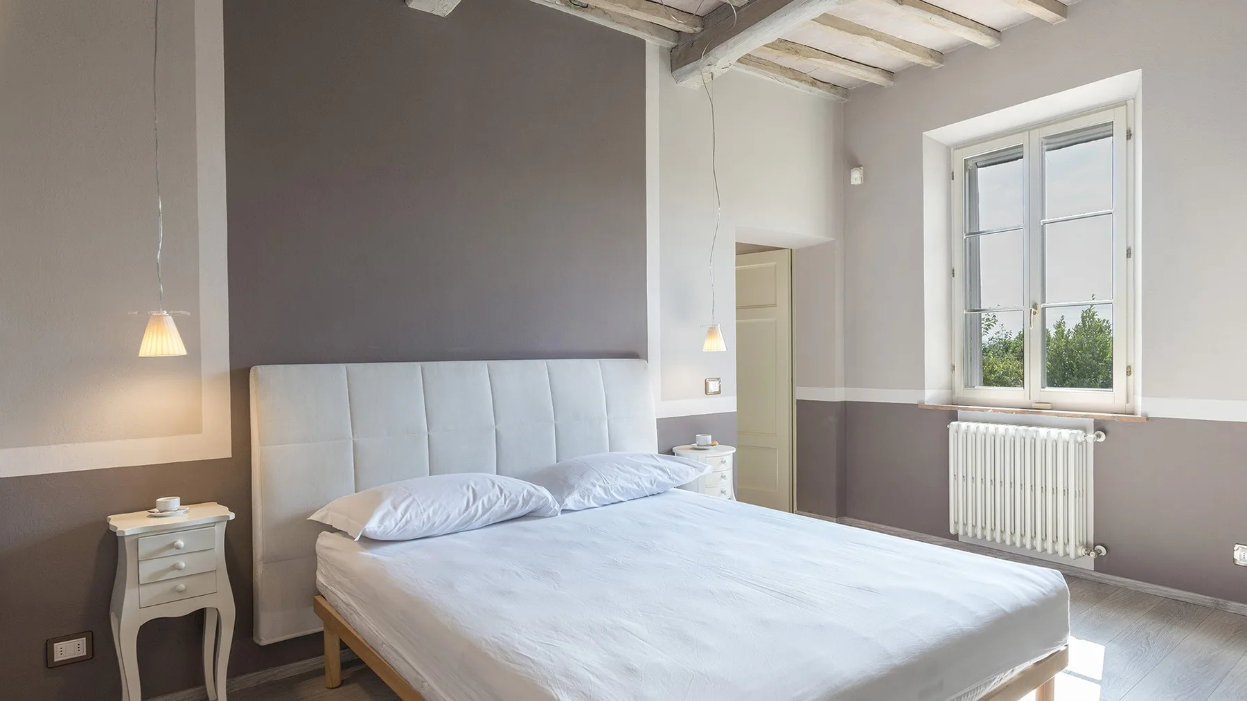 Un dormitorio con una cama grande, una mesita de noche y una ventana luminosa.