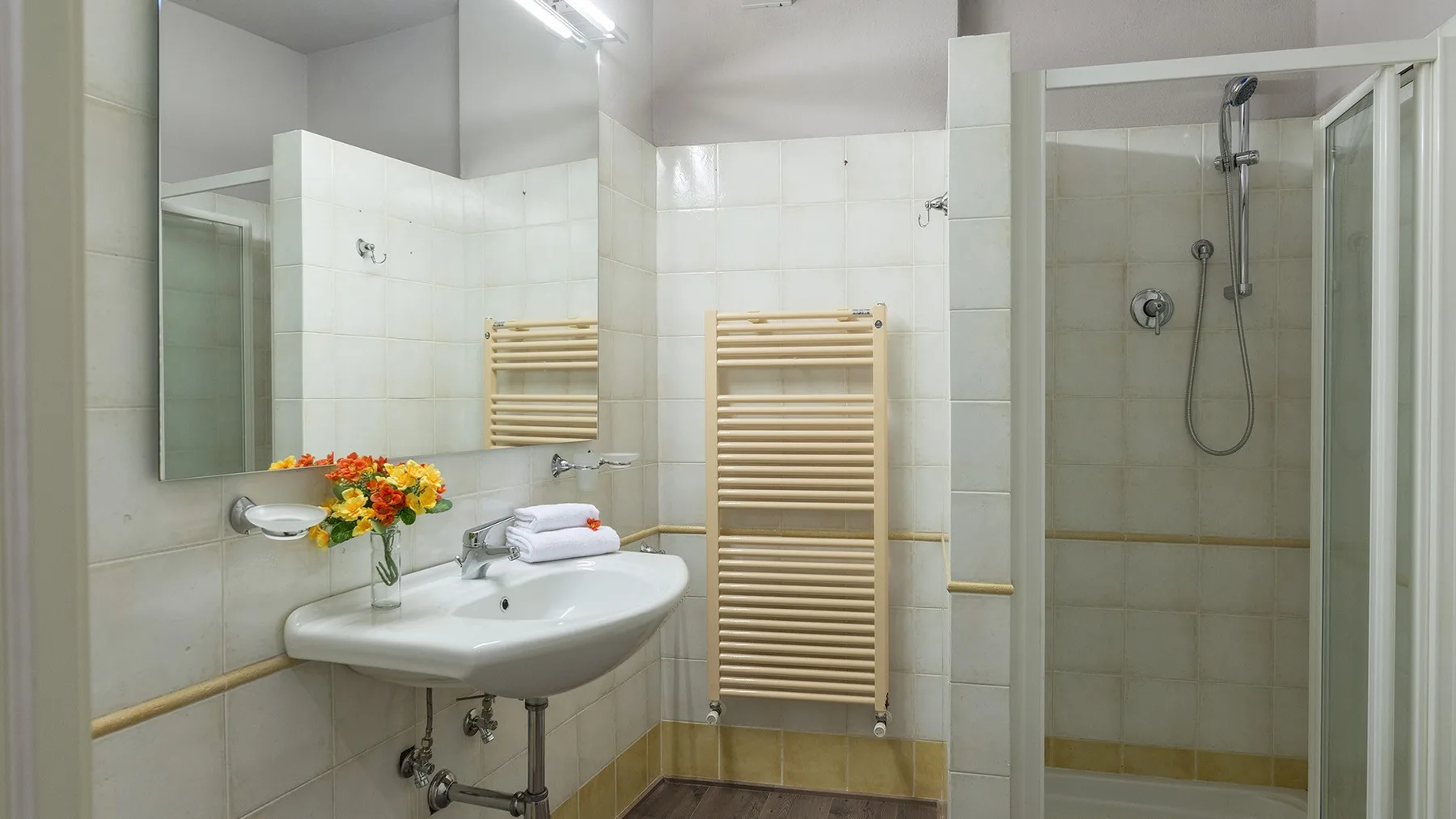 Un baño alicatado con lavabo, toalleros calefactados y ducha.