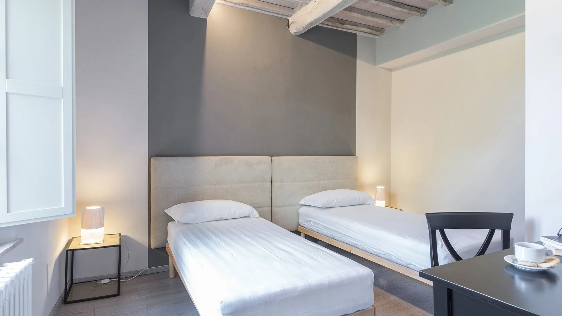Un dormitorio con dos camas individuales bajo vigas expuestas en el techo.