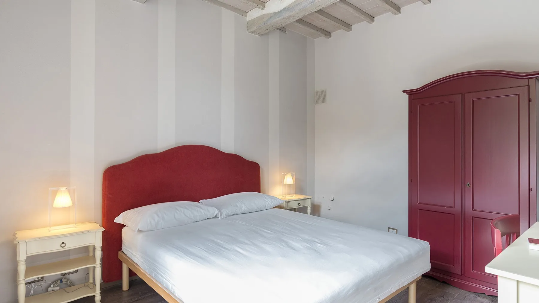 Un dormitorio con una cama, mesitas de noche y un armario grande.