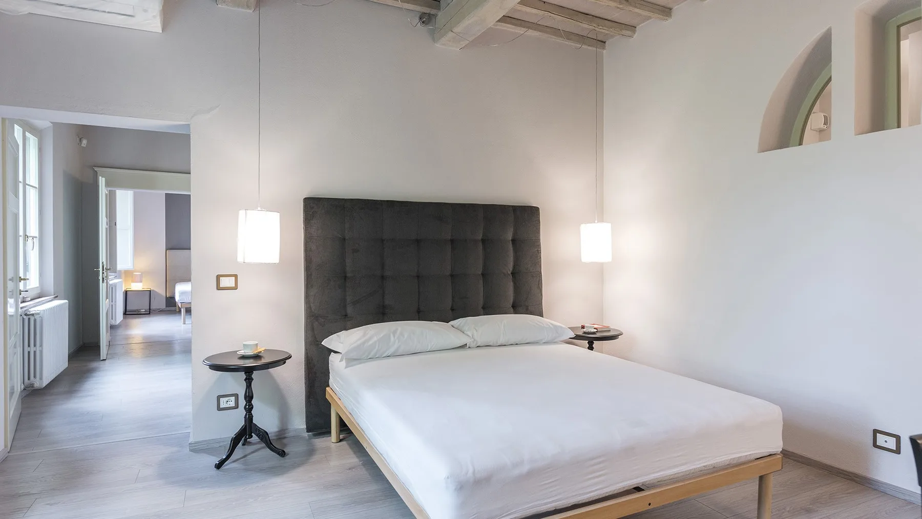 Un dormitorio con una cama grande, mesitas de noche y lámparas colgantes.