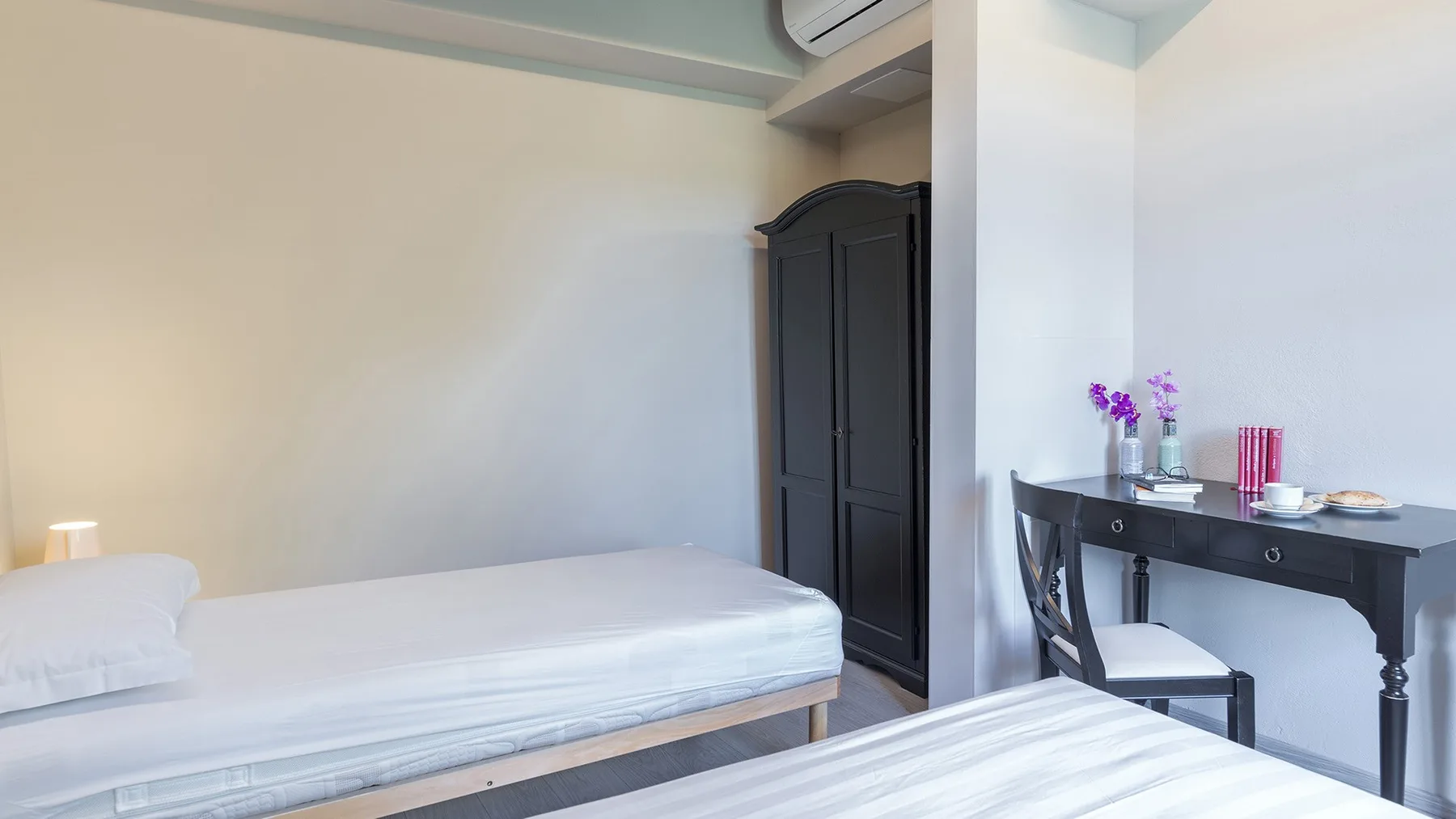 Un dormitorio con una cama, un armario oscuro y un escritorio.