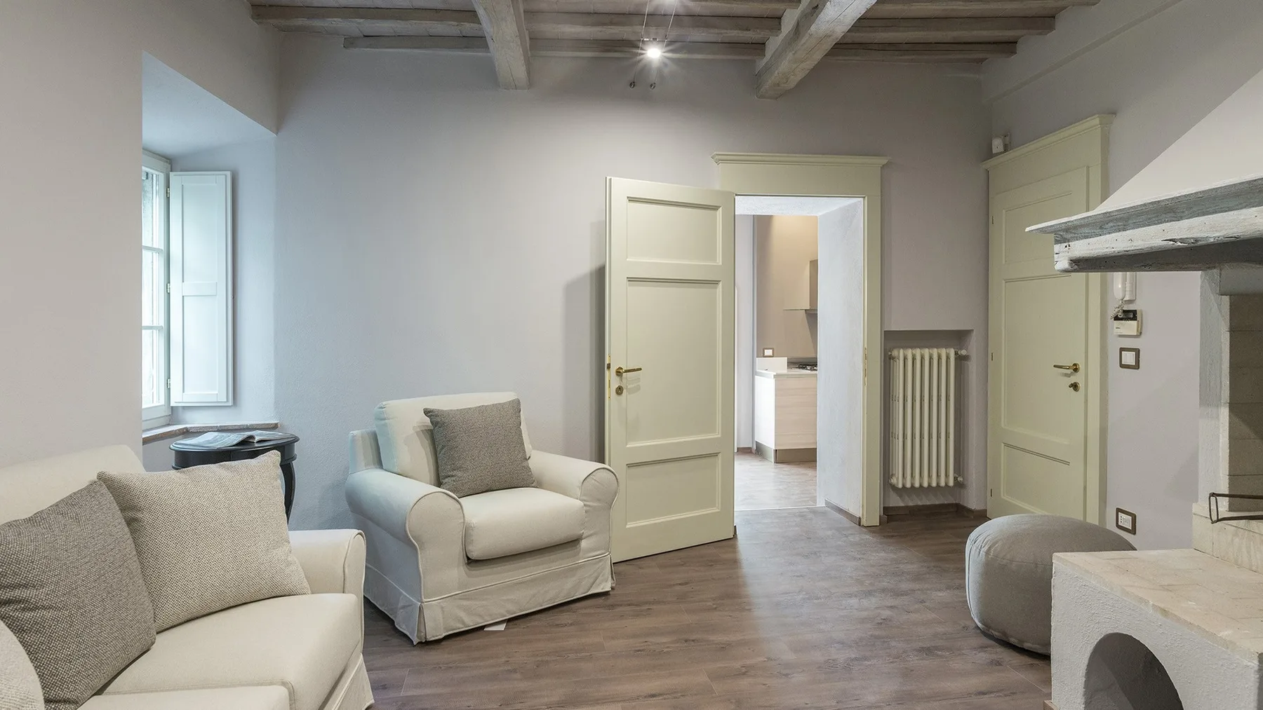 Una sala de estar con asientos claros y una puerta abierta.