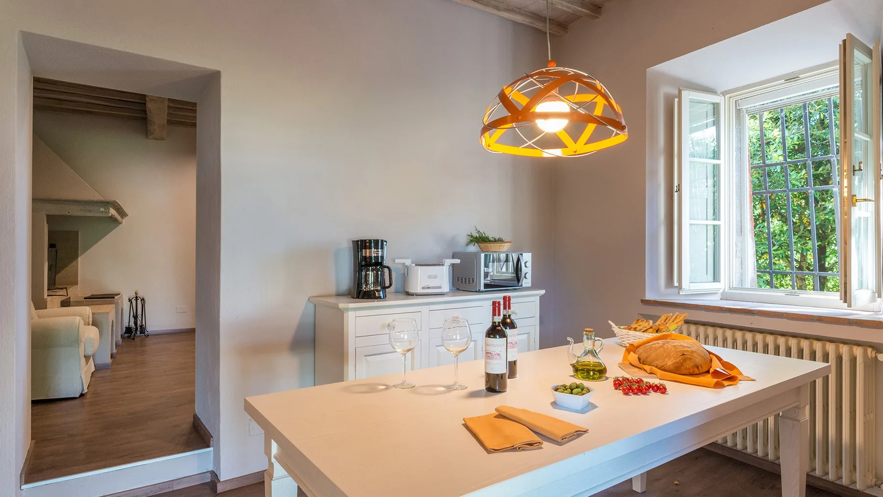 Un comedor luminoso con una mesa grande, comida y una ventana abierta.