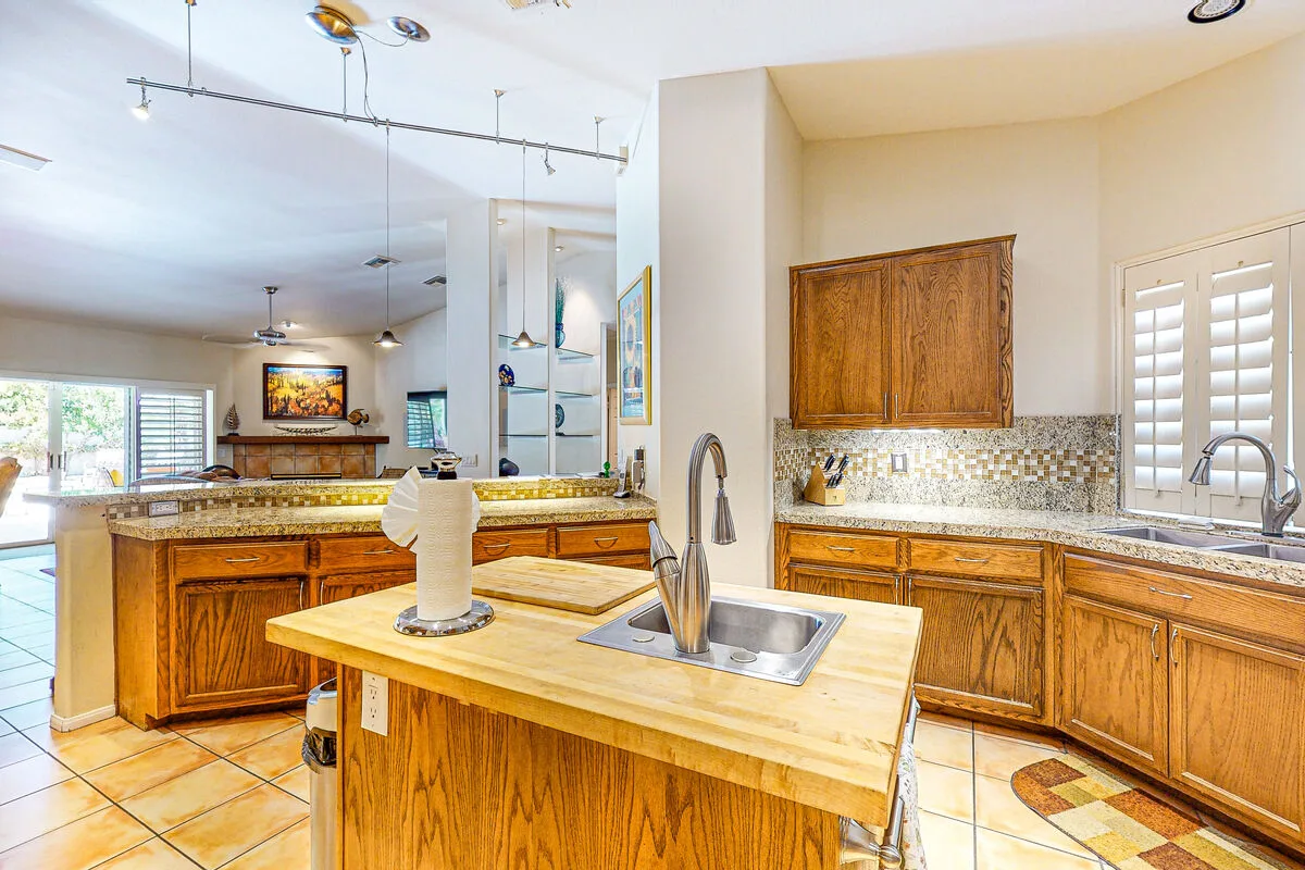 Una cocina luminosa con gabinetes de madera, una isla central y un comedor abierto.
