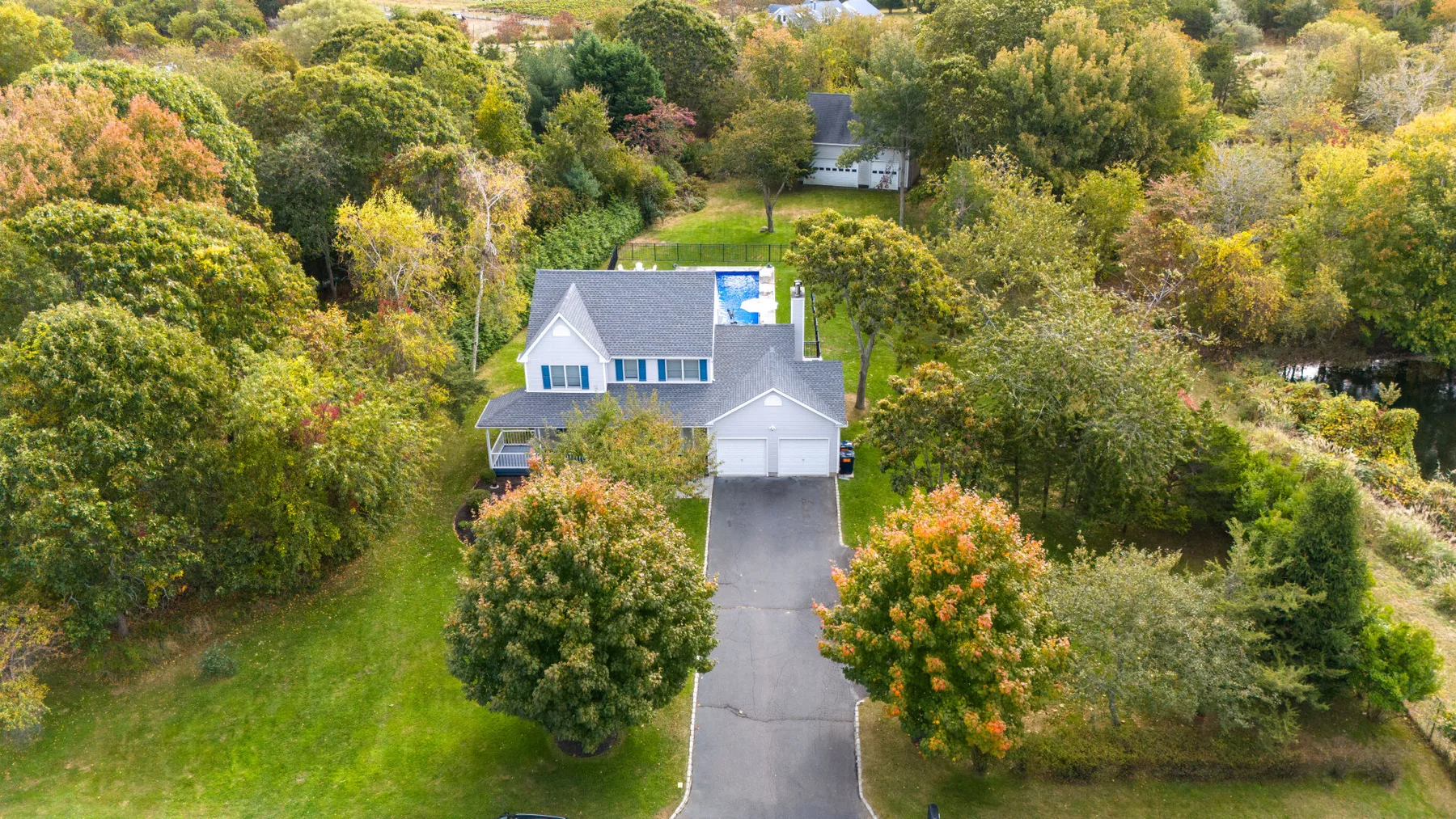 An aerial view of a house surrounded by trees and green lawn.
