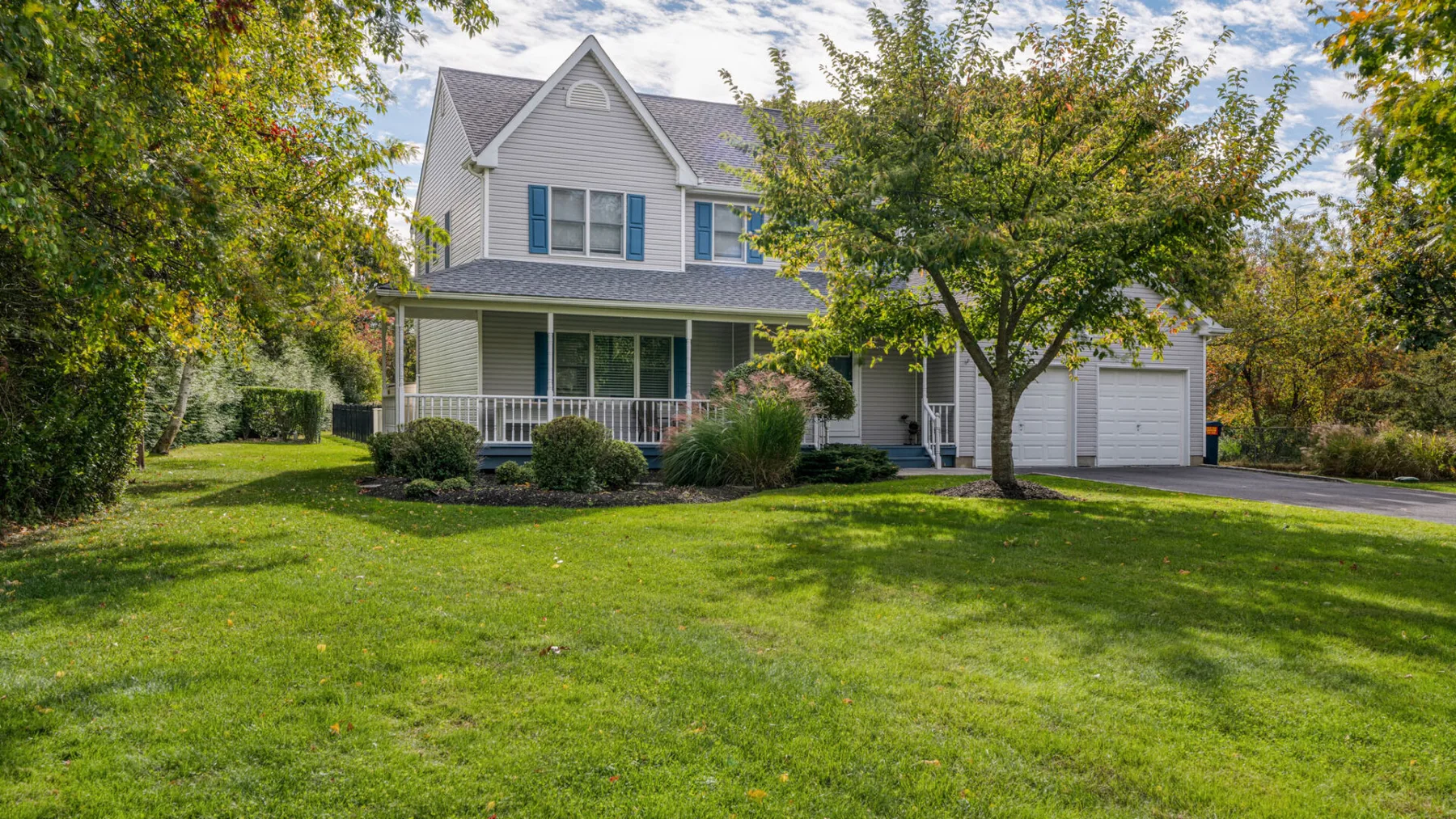 A two-story house with a front porch, garage, and broad green lawn.