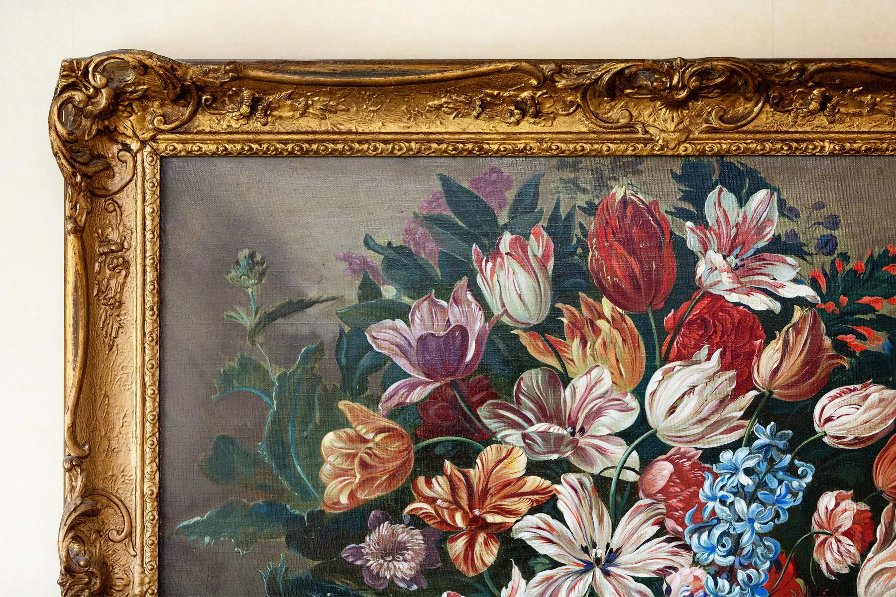 A framed painting of colorful flowers hangs on a light-colored wall.
