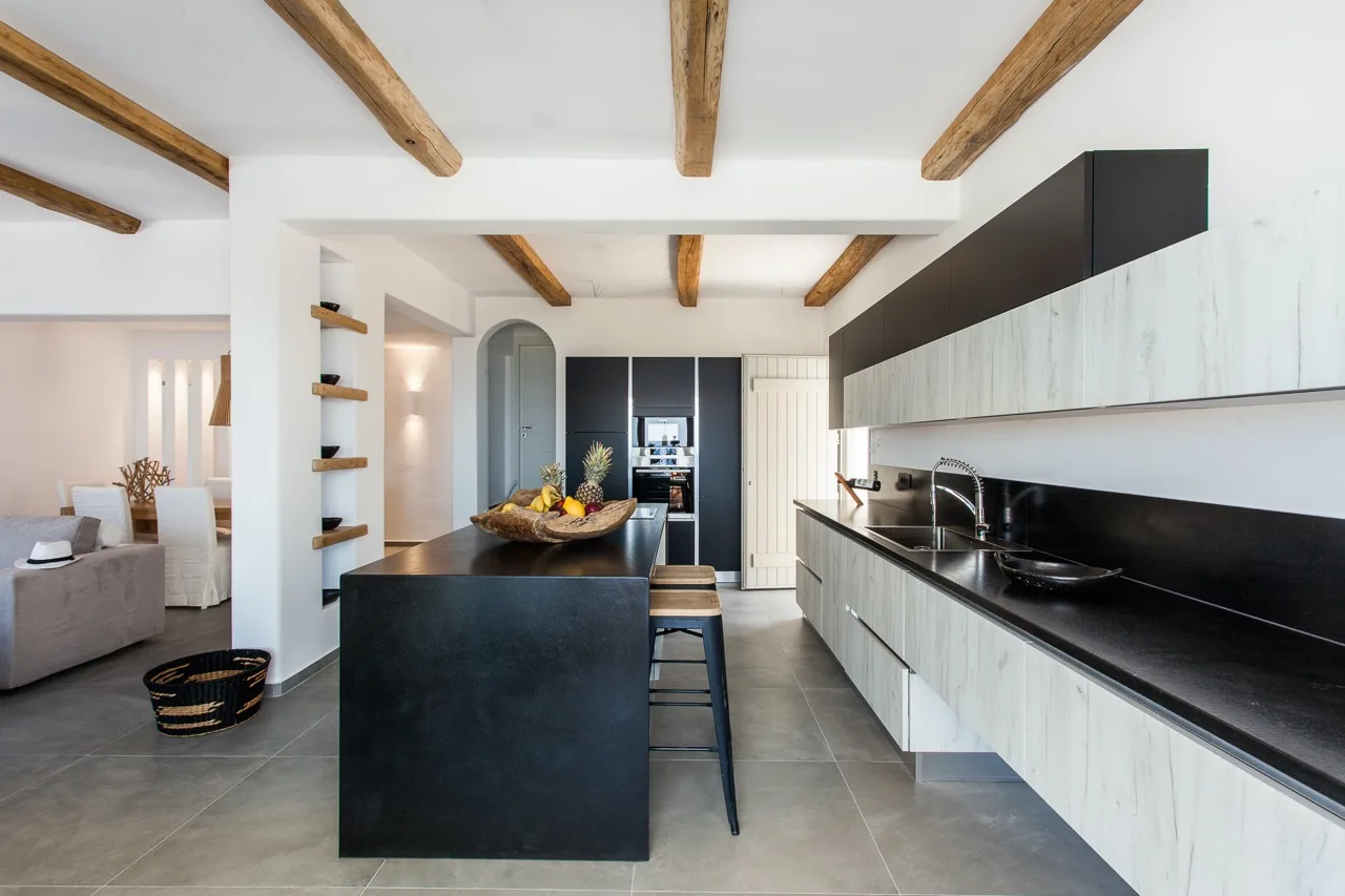 A modern kitchen with a dark island and long counters.