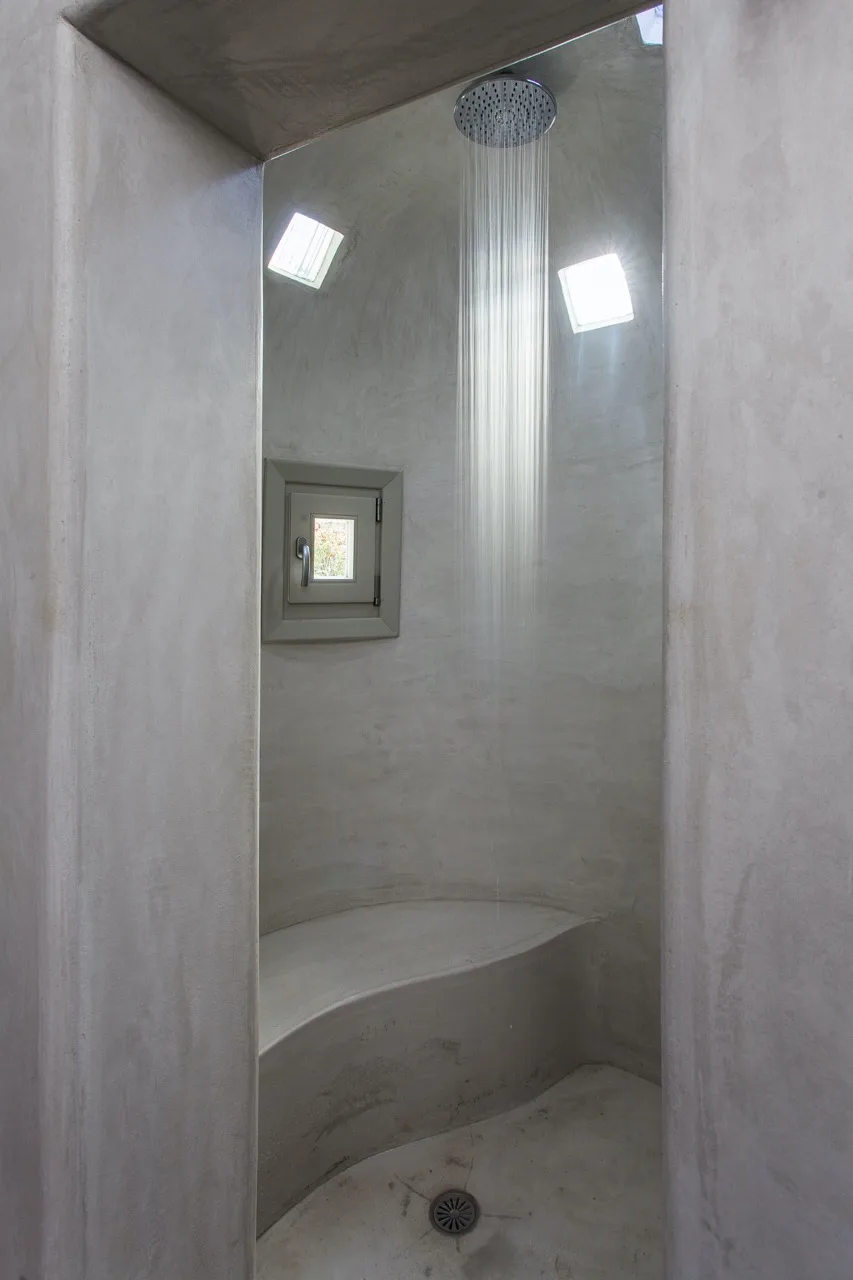A shower area with a rainfall showerhead and a built-in bench.