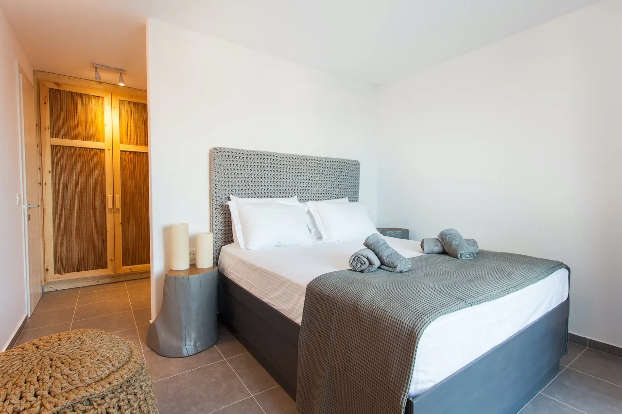A bedroom with a neatly made bed and a woven headboard.