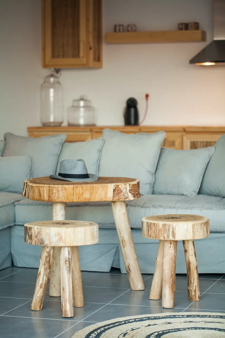 A living room with pale seating, a wooden coffee table, and two small stools.