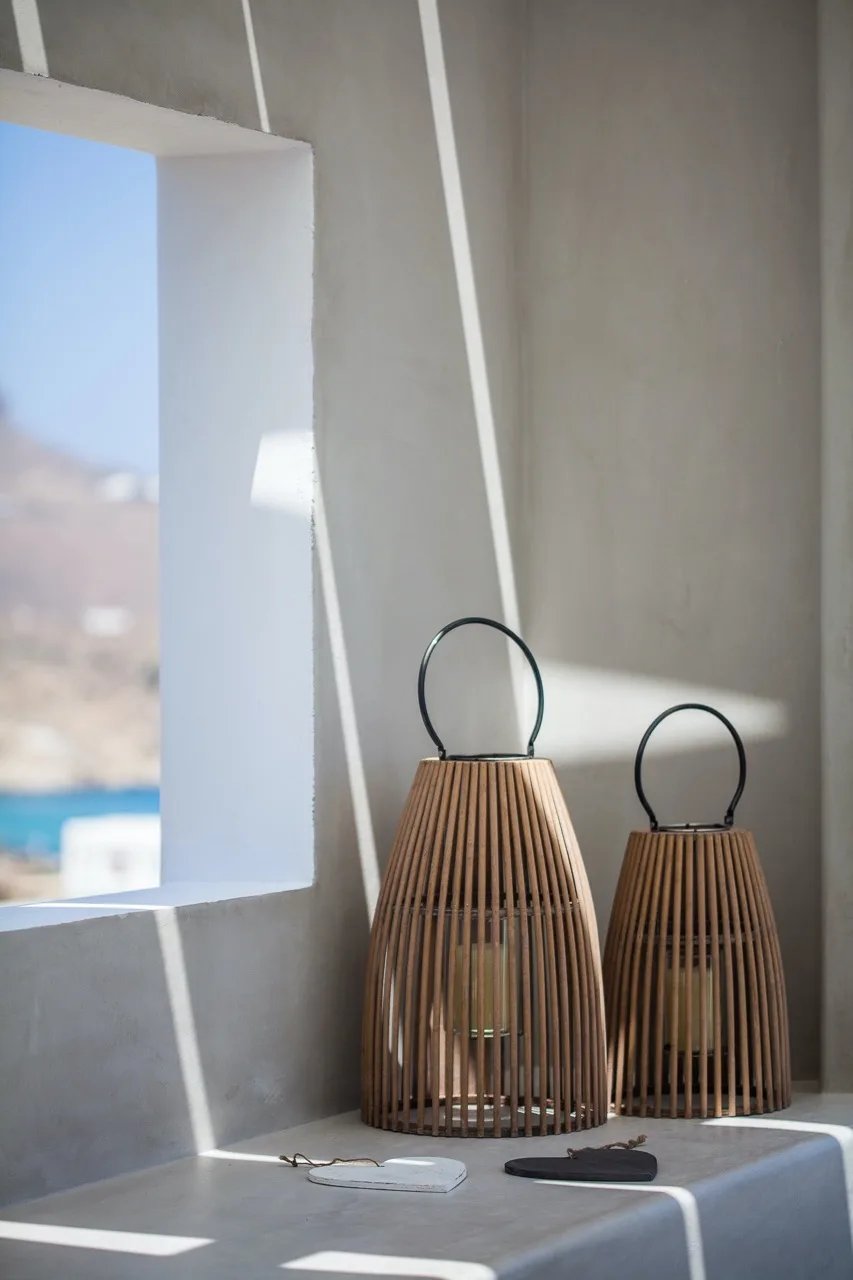 Two decorative lanterns sit on a gray ledge beside a large window.