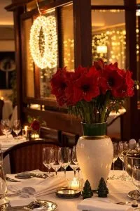 Representative hotel space: A warmly lit restaurant dining table is set with glassware and a vase of red flowers.