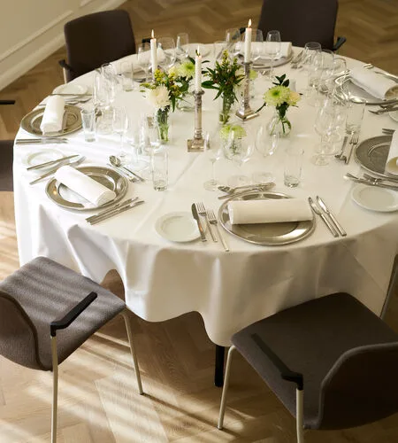 Representative hotel space: A dining table is set with place settings, candles, and small floral arrangements.
