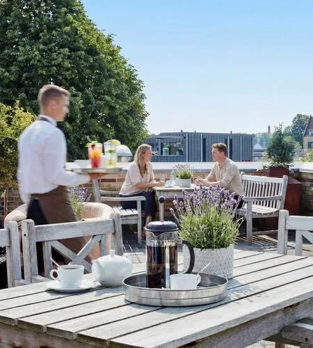 Representative hotel space: An outdoor dining terrace with wooden seating and a table set for refreshments.