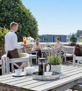 Representative hotel space: An outdoor dining patio with people seated around a table.