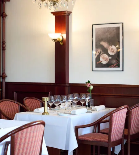 Representative hotel space: A dining room with a table set with glassware and upholstered seating.
