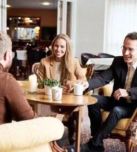 Representative hotel space: People sit around a table in a bright dining area.