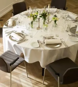 Representative hotel space: A round dining table is set with plates, glassware, and floral arrangements.