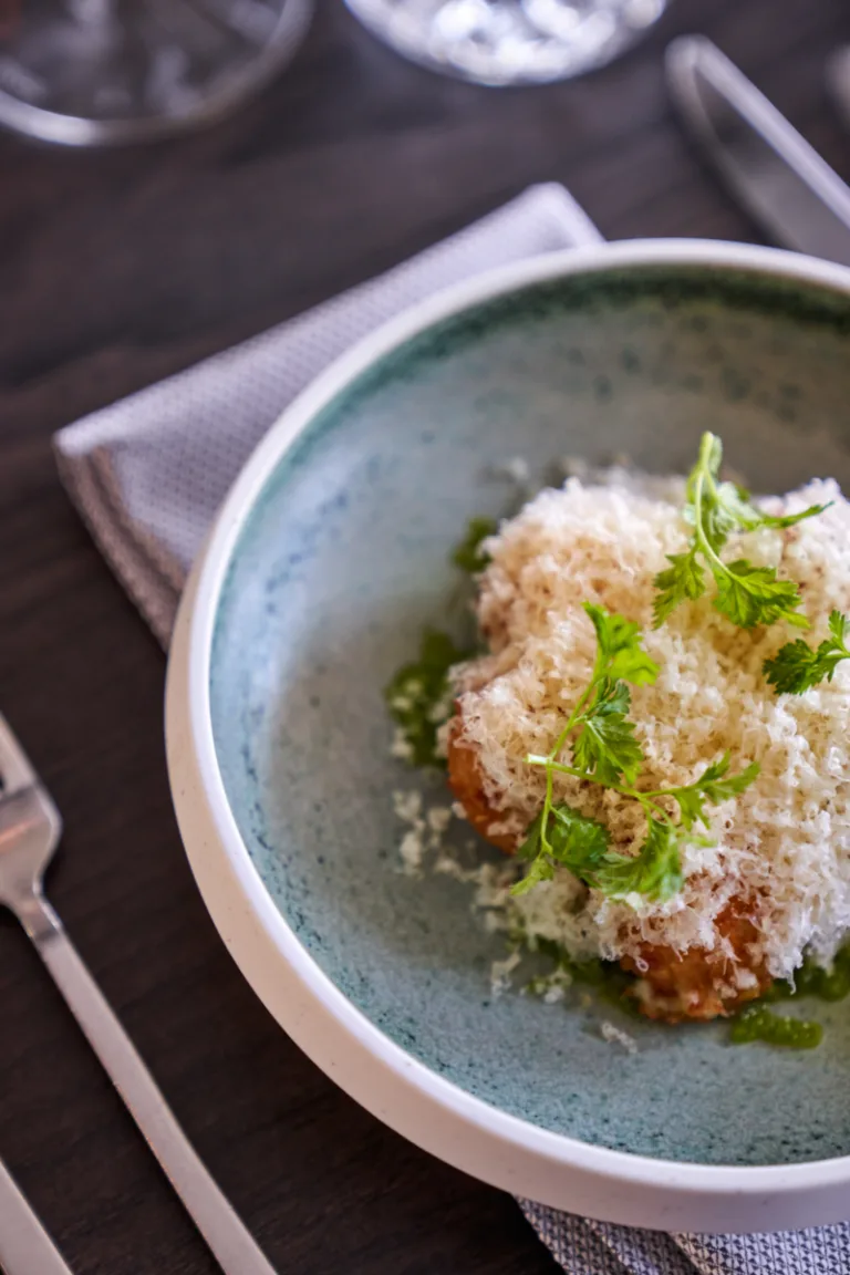 Representative hotel space: A plated dish topped with grated cheese and fresh green herbs.