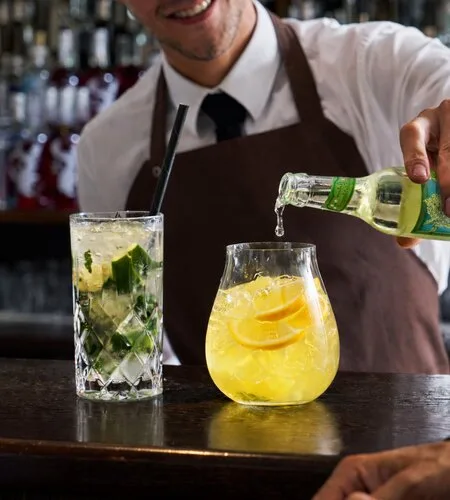 Representative hotel space: A bartender pours a drink beside two cocktails on a bar counter.
